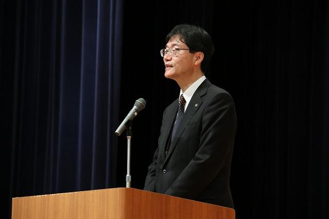 壇上に上がり挨拶をするスーツ姿の鈴木市長の写真