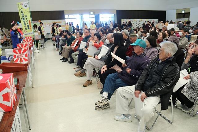 抽選会会場に集まった大勢の参加者たちが椅子に座っている写真