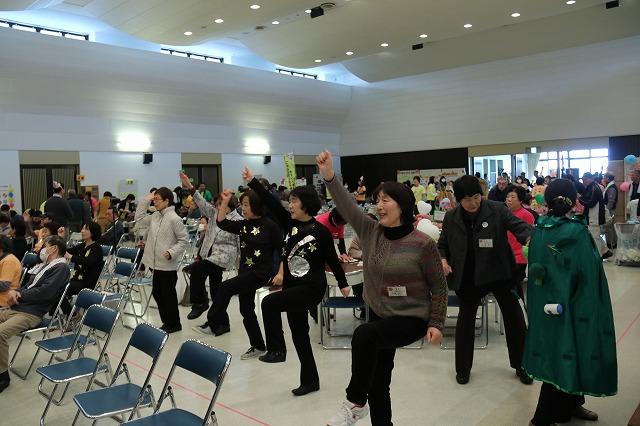 会場内で離席して音楽に合わせて「にこっち体操」をしている参加者たちの写真