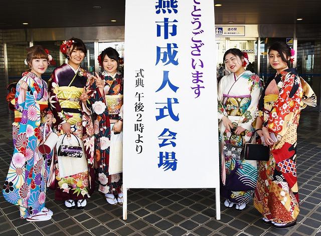 「成人式」看板の左右に並んだ振袖姿の5人の女性新成人たちの写真