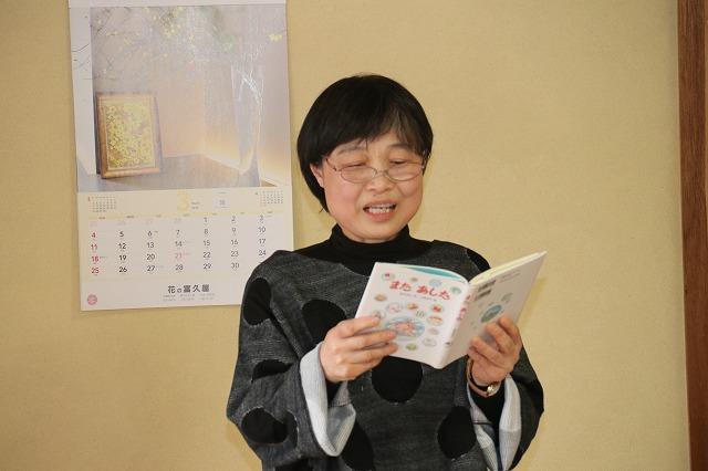 鈴木和江先生の本を手に持ち、詩を声を出して読んでる「七色の会」の別の女性の写真