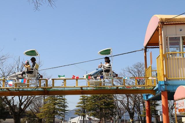 高い場所に設置されたサイクルモノレールで遊ぶ親子の様子
