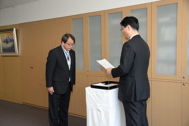 辞令交付式で市長が読み上げる辞令を聞いている松村金司さんの写真