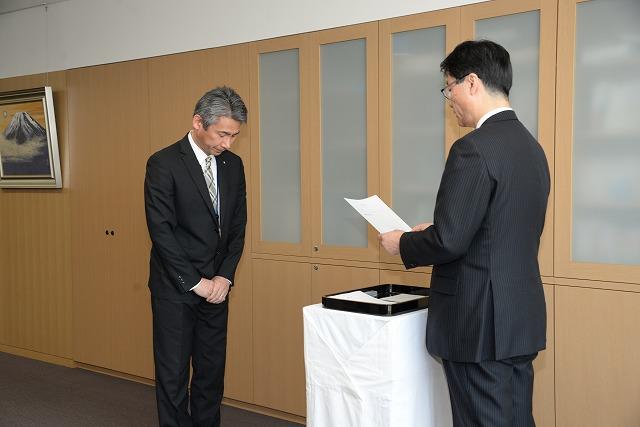 辞令交付式で市長が読み上げる辞令を聞いている小泉浩彰さんの写真