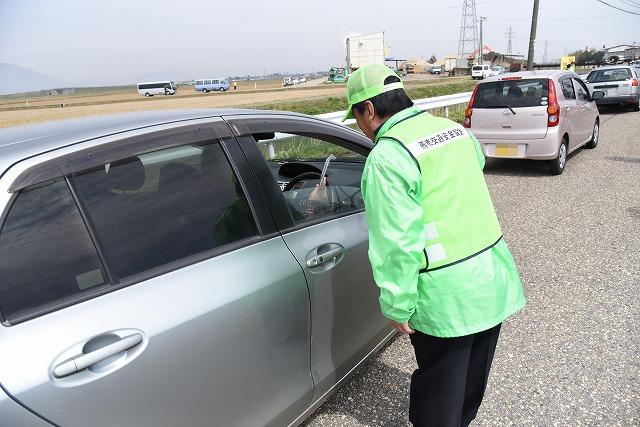 ドライバーに交通安全を直接訴えている緑色の制服を着た交通安全隊たちの様子の写真