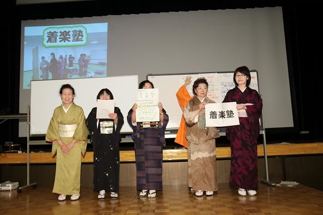 壇上で活動内容を発表している着物姿の5人の女性たちの写真