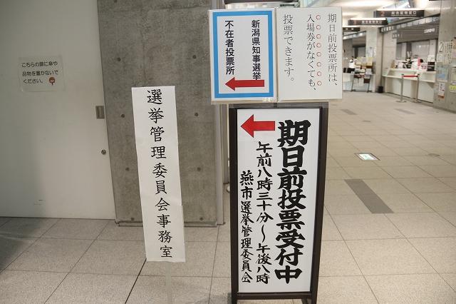 施設内の曲がり角に、「期日前投票受付中」などの看板が複数立てられている写真