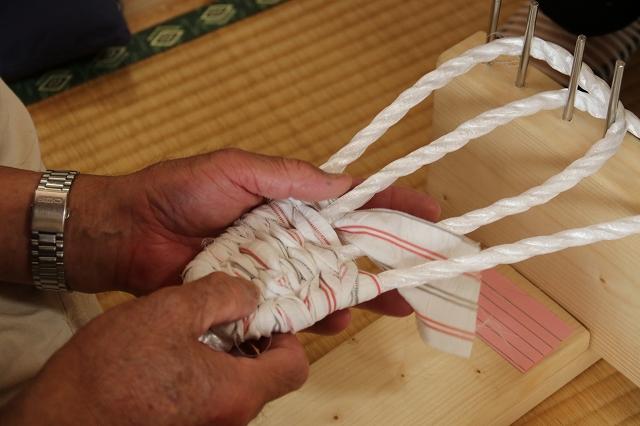 張り詰めた紐に布を3分の1ぐらい織り込んでいる様子の写真