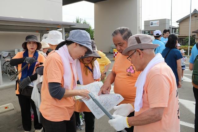 地図を見ながら作戦を立てている同じオレンジのTシャツを着たグループの様子の写真