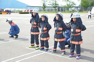 消防服を着た子供たちが、横に並んで背中に手をまわしている写真
