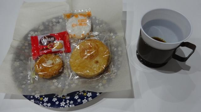 おせんべいなどのお菓子が置かれているお皿の横に、コーヒーの入ったコップが置かれている写真