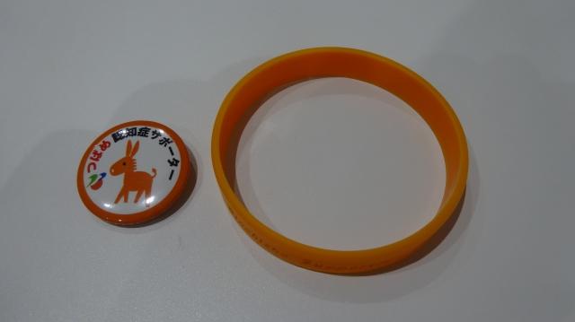 オレンジのロバのキャラクターが描かれたバッジの横に、オレンジ色のリングが並んでいる写真