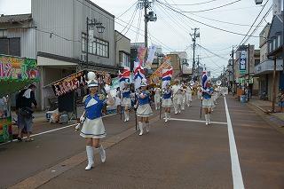青と白の衣装を着た女性たちが、路上を行進している写真