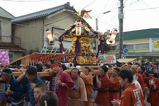 色とりどりのはっぴを着た人たちが金色の神輿を担いでいる写真