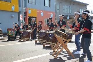 路上で横一列に並んで和太鼓を演奏する人たちの写真