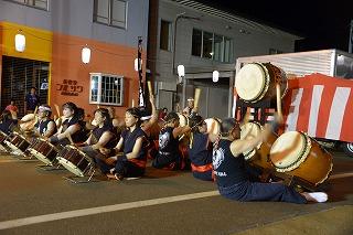 小さな太鼓と大きな太鼓を演奏している人たちの列が背中合わせになっている写真