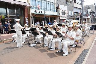 白い制服を着た人たちが並んで座り、楽器を演奏している写真