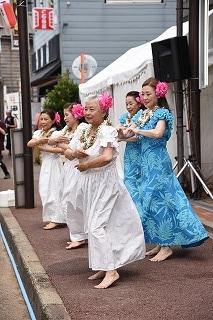 ピンクの花飾りをつけて踊っている女性たちの写真