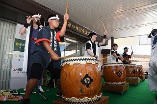 はちまきをした男性が、四人並んで和太鼓を演奏している写真