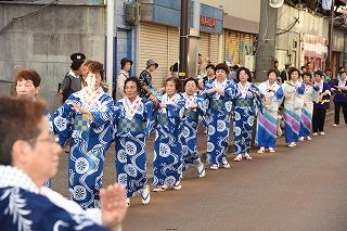 青と白の和服を着た女性たちが、列をなして練り歩いている写真