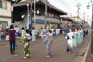 様々な色の和服を着た女性たちが、路上を踊り歩いている写真