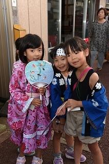 三人の女の子たちが、うちわを手に集まっている写真
