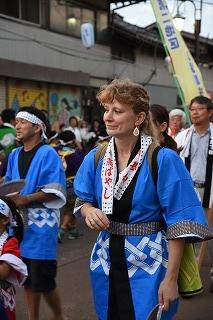 青いはっぴを着て歩いている外国人の女性の写真