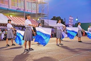 女子中学生たちが、白と青の旗を持ち上げている写真
