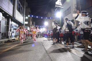 踊りながら夜の街を練り歩いている参加者たちの写真