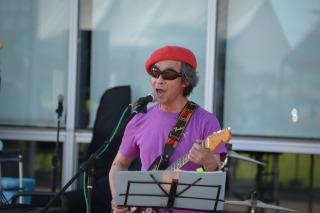 赤いベレー帽と紫のシャツを着た人がギターを演奏している写真