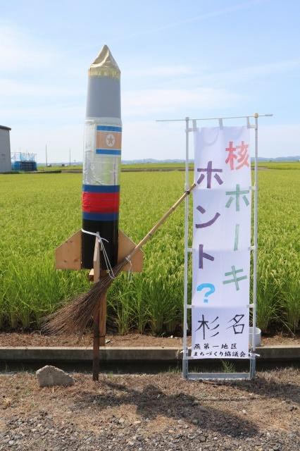 国旗が描かれたロケットの模型に、箒が括り付けられている写真