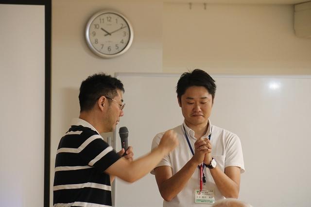 講師が、両手を組んでいる職員の横に立ち、動かし方を伝えている写真