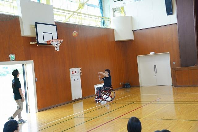 車椅子の男性が、ゴールに向かってボールを投げている写真