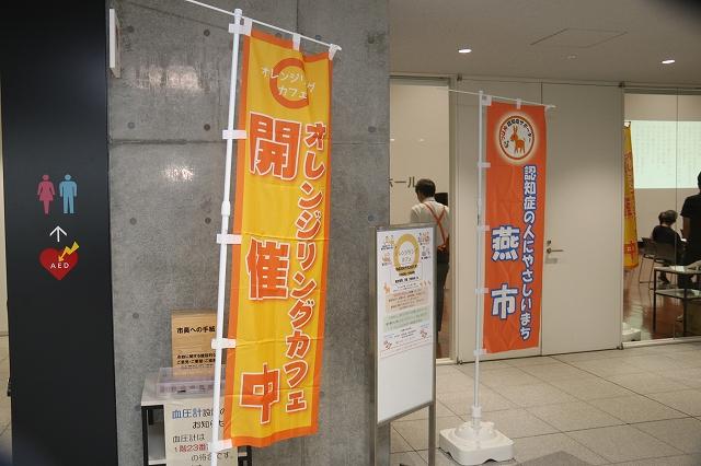 会場の入口で、オレンジ色ののぼりが二本立てられている写真