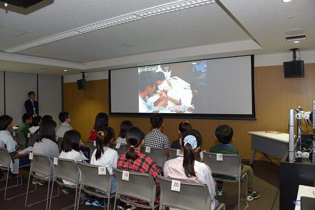 スクリーンに映されているスライドの映像を見ている小学生たちの様子の写真