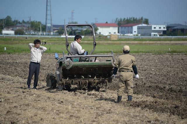 トラクターで作業中の男性に話しかけている写真