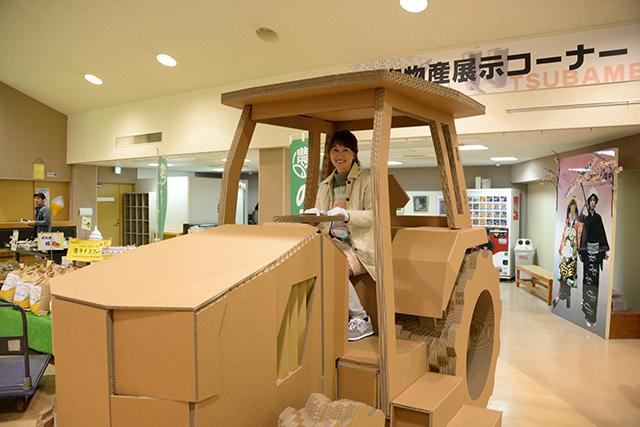 会場内で段ボール製のトラクターを操縦する女性の写真