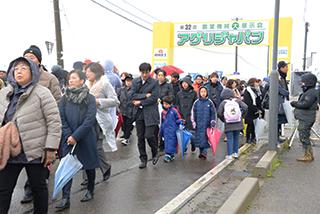 傘を手にした参加者たちが雨の中集まっている写真