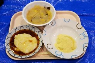 青いマットの上の白いトレーの上にあるお皿に盛り付けられた砂糖醤油のかかった餅とさつま汁ときな粉の写真