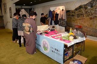 テーブル上に遊休品を陳列し和服姿の販売している女性の写真