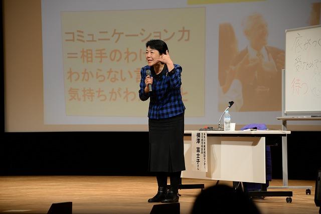 壇上でジェスチャーを駆使しながら子育てに携わり方などを話す横澤さんの写真