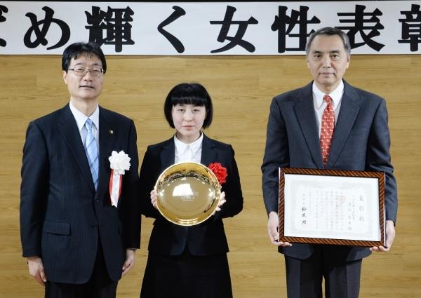 市長と並んで立つ盾を持つ女性と賞状を持つ男性の写真