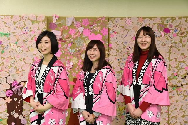 ピンクのはっぴを着た3人の女性が、笑顔で並んでいる集合写真