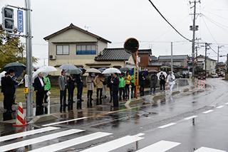 傘をさした人たちが、列になって歩道に並んでいる写真