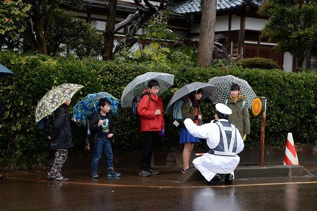 傘をさした子どもたちに対し、職員がしゃがんで指導をしている写真