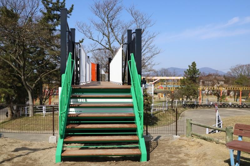 緑色の手すりがある、公園内の階段の写真