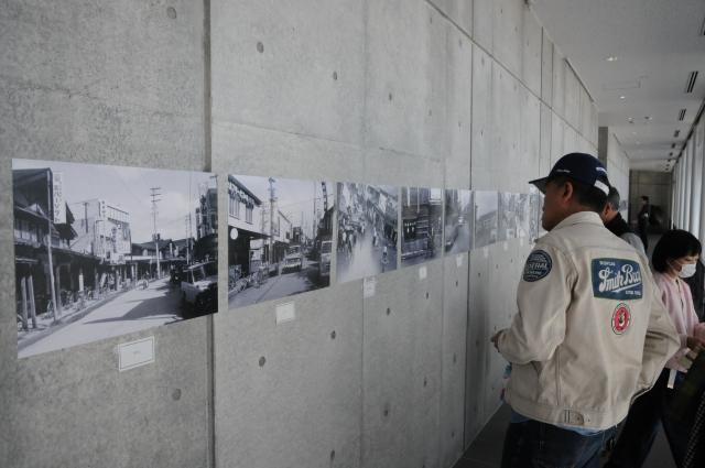 昭和の白黒の写真が展示されているのを見ている方々の葉数の写真