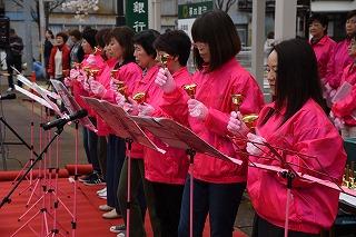 ハンドベルを鳴らしているピンクのジャンパーに身を包んだ女性たちの様子の写真