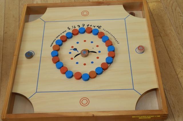 赤と青の丸いコマが円状に並べられたゲームのスタート状態のカロムの写真