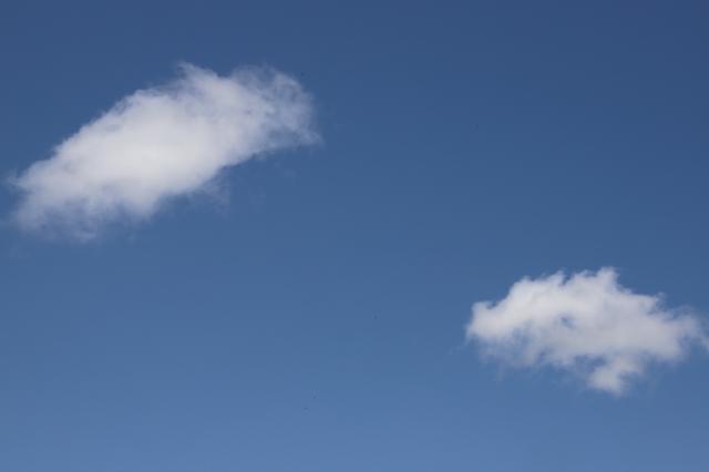 白い雲が2つ浮かんでいる晴天模様の空の写真